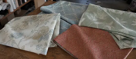 Muestras de telas decorativas con diseños y colores suaves sobre un mesón