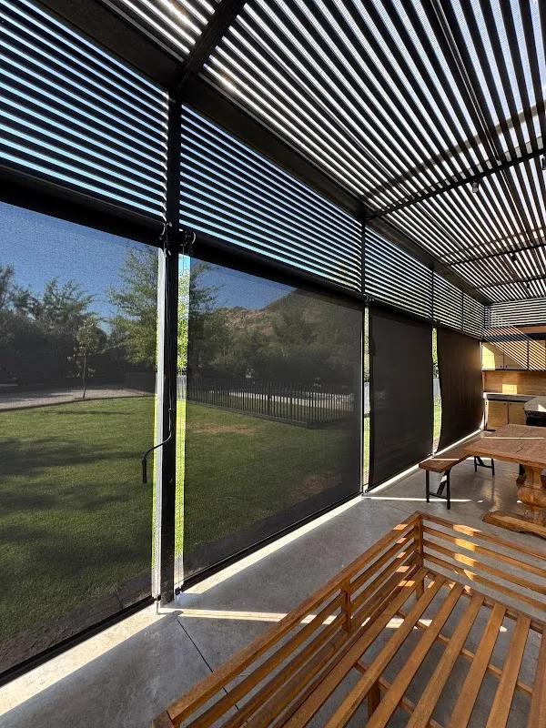 Toldos verticales cerrando el costado de una terraza con pérgola, con el jardín visible a través de la tela