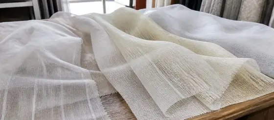 Muestras de velos y gasas blancas y crudas extendidas sobre un mesón